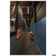 Lange Halle mit blauen und schwarzen Wänden, Netztrennwänden und Tischtennisplatten in einem Sportzentrum.