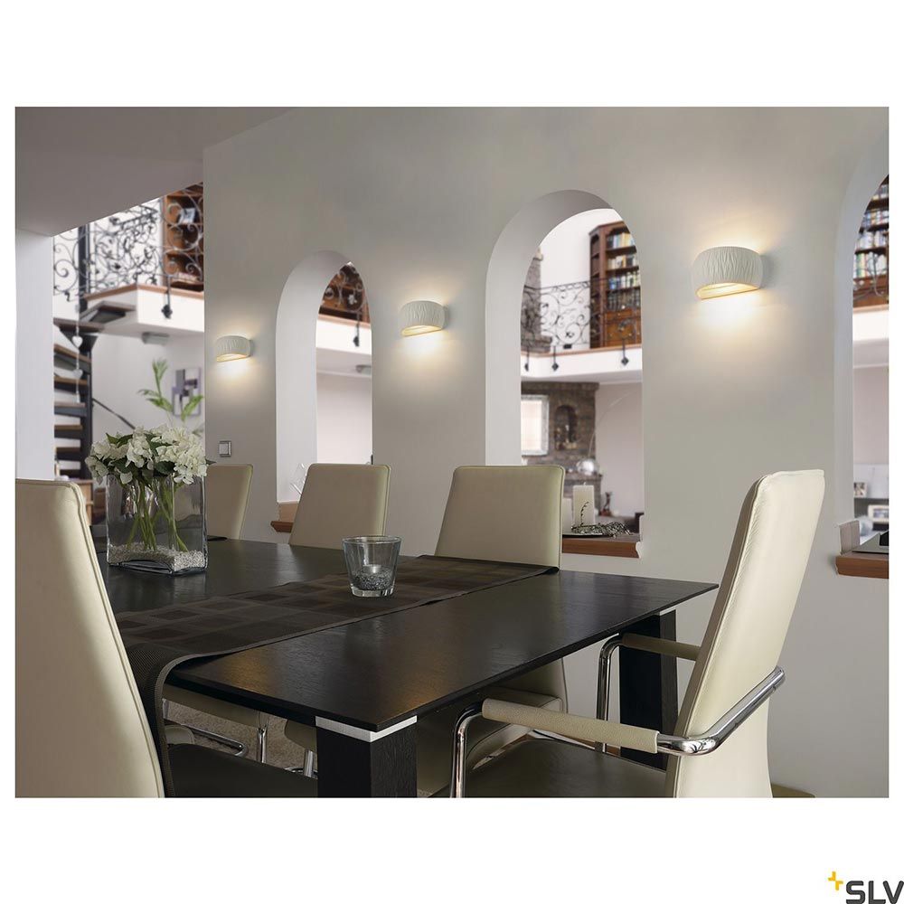 Moderne weiße Plastra Curved Wandaufbauleuchte in einem stilvollen Essbereich mit elegantem Tisch.