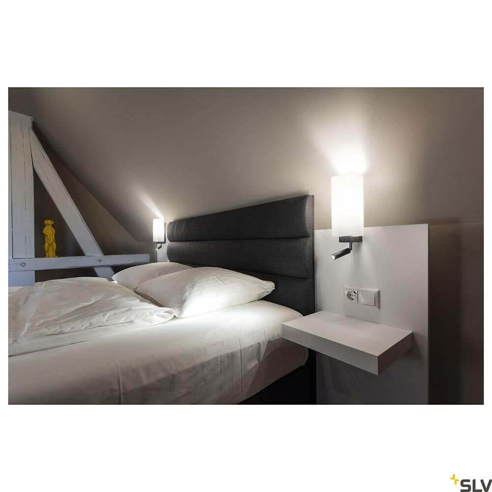 Quadrass LED Wandleuchte neben einem Bett in einem modernen Schlafzimmer mit warmweißem Licht.