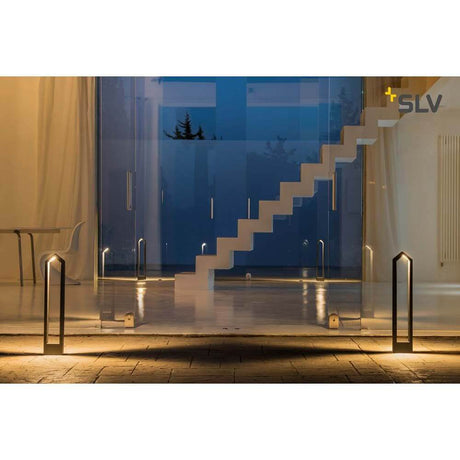 Rascali 65 Pole LED luminaire sur pied d’extérieur anthracite 3000K devant un bâtiment moderne avec escalier la nuit.