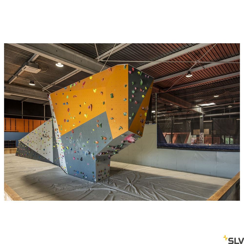 Bouldernwand in einer Kletterhalle mit bunten Griffen und Sicherheitsmatten im Innenbereich.