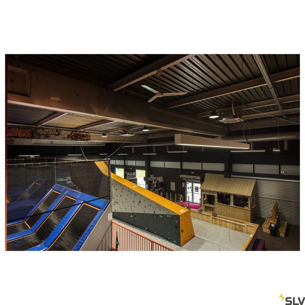 Blick auf eine Indoor-Sportanlage mit Trampolinen und Kletterwand, beleuchtet von SLV Pendelleuchten.