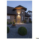 Rusty LED Wandaufbauleuchte Up&Down Outdoor Rost CCT an einem modernen Haus mit Steinmauer und Garten.