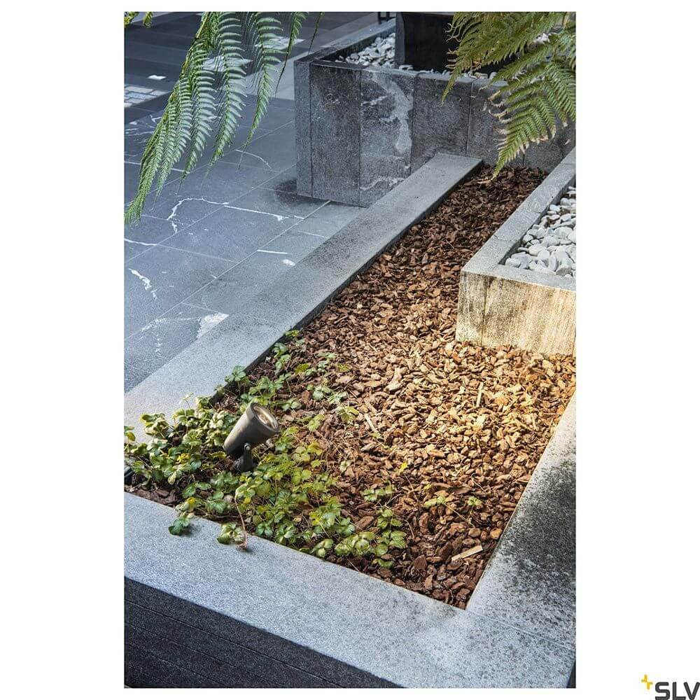 Samrina Single Outdoor Erdspießleuchte Schwarz im Garten, beleuchtet mit recyceltem Material.