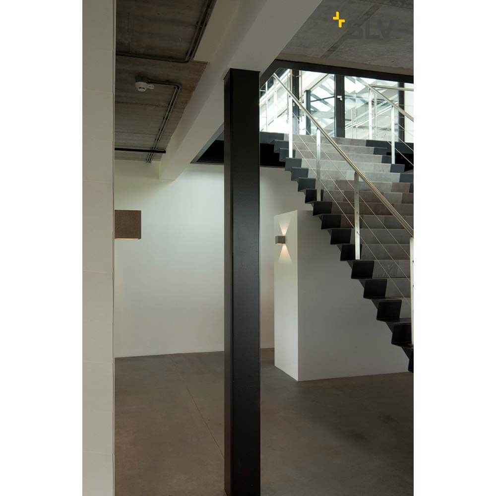 Solid Cube Wandleuchte QT14 Sandstein in modernem Wohnraum mit Treppe und minimalistischer Architektur.