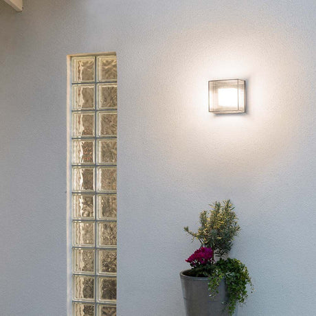 Sanremo LED Applique da esterno Grigia su una parete con piante e parete di vetro.