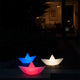 Schwimmfähige Akku-LED-Dekolampe im Origami-Design, leuchtet in Blau, Rot und Weiß im Garten.