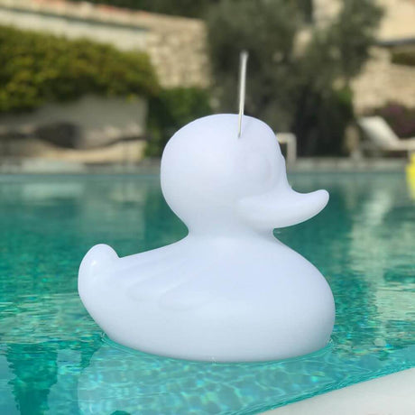 Den flydende genopladelige LED-lampe Duck-Duck S Hvid svømmer i poolen og lyser kreativt.