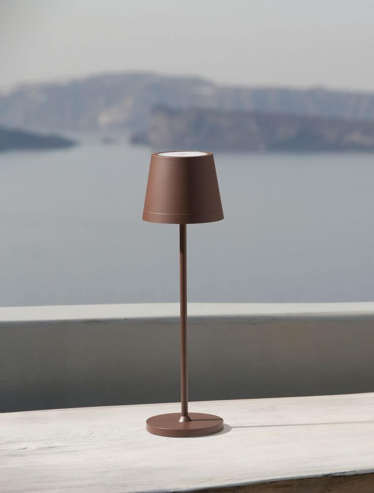 Seina LED Außentischleuchte 3000K IP54 in Braun auf einem Tisch mit Blick auf das Wasser.