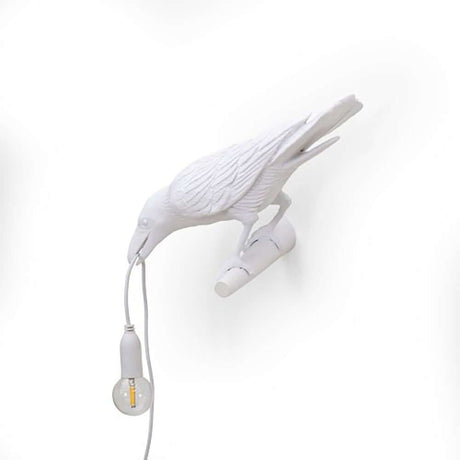 Applique extérieure Seletti Bird regardant vers la gauche avec corbeau blanc et câble lumineux.