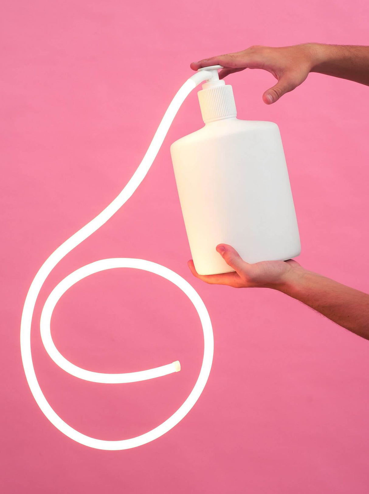 Seletti Daily Glow Soap LED-Tischleuchte Warmweiß – weiße Seifenform-Lampe aus Kunstharz mit warmweißem LED-Licht, gehalten von Händen vor rosa Hintergrund