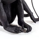 Alt Tag: Seletti Monkey Lamp Dekoleuchte Outdoor sitzend Schwarz sitzender Affe mit Glühbirne, detailreiche schwarze Oberfläche