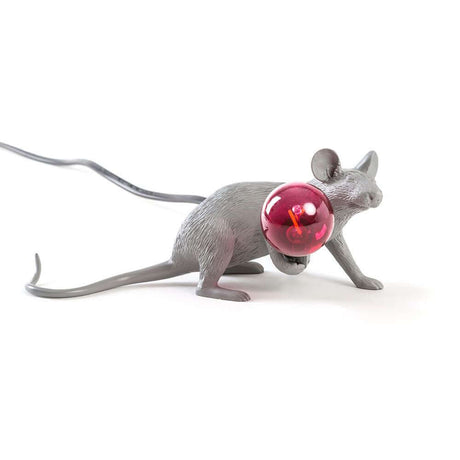 Découvrez la lampe de table allongée USB Seletti Mouse Lop LED avec une souris et une ampoule rouge sur une table.