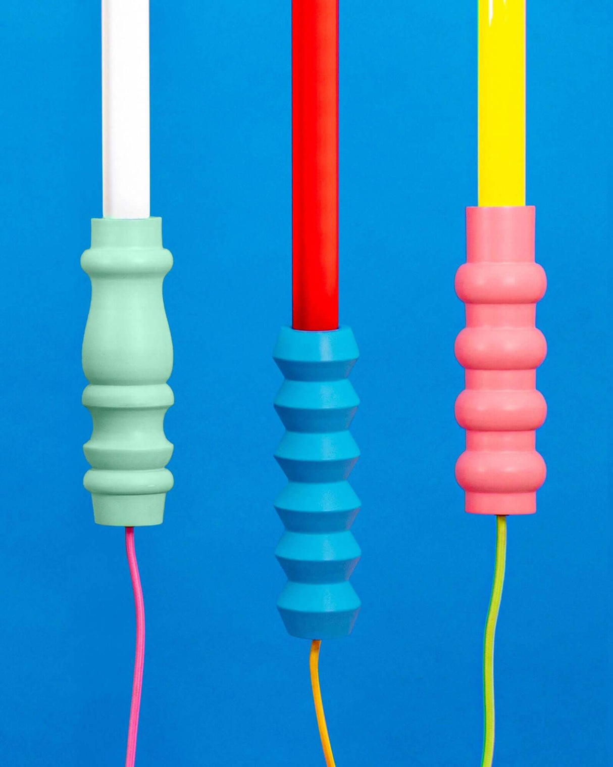 Seletti Superlinea LED-Leuchte 141cm – bunte Stehleuchte mit pastellgrün, blau und rosa Griffen vor blauem Hintergrund