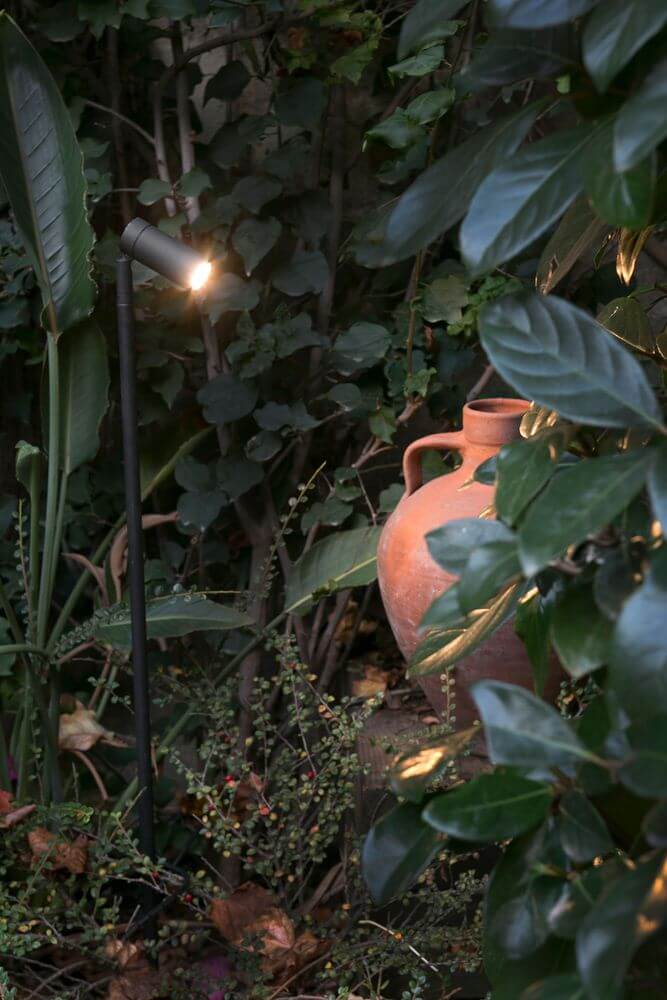 Seth LED Spießstrahler Schwarz 40° IP44 beleuchtet eine Terrakotta-Vase im Garten.