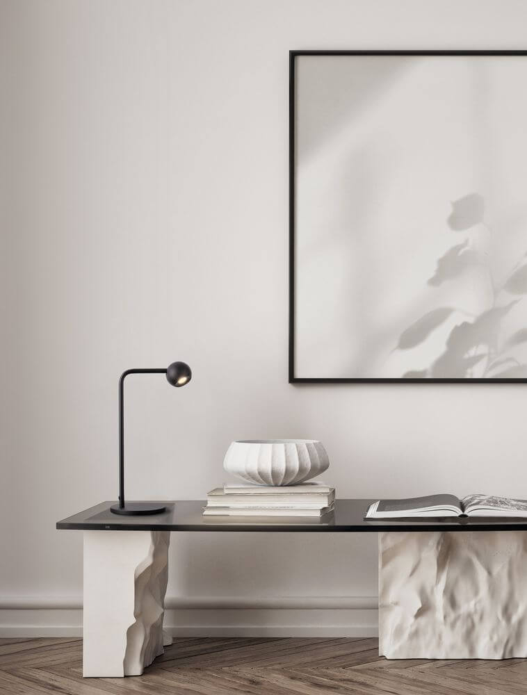 Sfera Tischleuchte 3000K Schwarz auf einem eleganten Tisch mit Kunstwerk und Deko-Objekten.