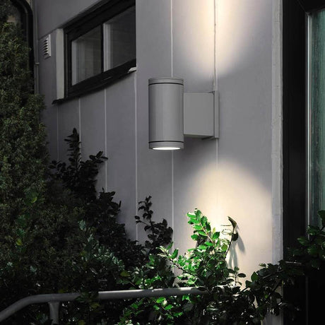 Siracusa Außen-Wandlampe Grau, klares Glas, Reflektor an einer Wand mit Pflanzen.