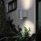 Siracusa Außen-Wandlampe Grau, klares Glas, Reflektor an einer Wand mit Pflanzen.