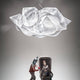 Slamp Hängelampe Fabula Prisma Transparent über einem futuristischen Setting mit Figuren.