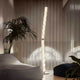 Slamp Hugo Stehleuchte 207cm aus Lentiflex-Kunststoff im modernen Wohnraum mit Sofas und Pflanzen.