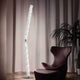 Slamp Hugo Stehleuchte 207cm aus Lentiflex-Kunststoff neben einem modernen Sessel in einem gemütlichen Raum.