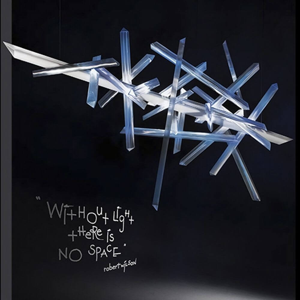 Slamp LED Hängelampe La Traviata Lichtskulptur an einer dunklen Wand mit inspirierendem Zitat.