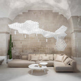 Slamp Nuvem hängendes Lichtobjekt über modernem Sofa in stilvollem Raum mit Steinmauer.
