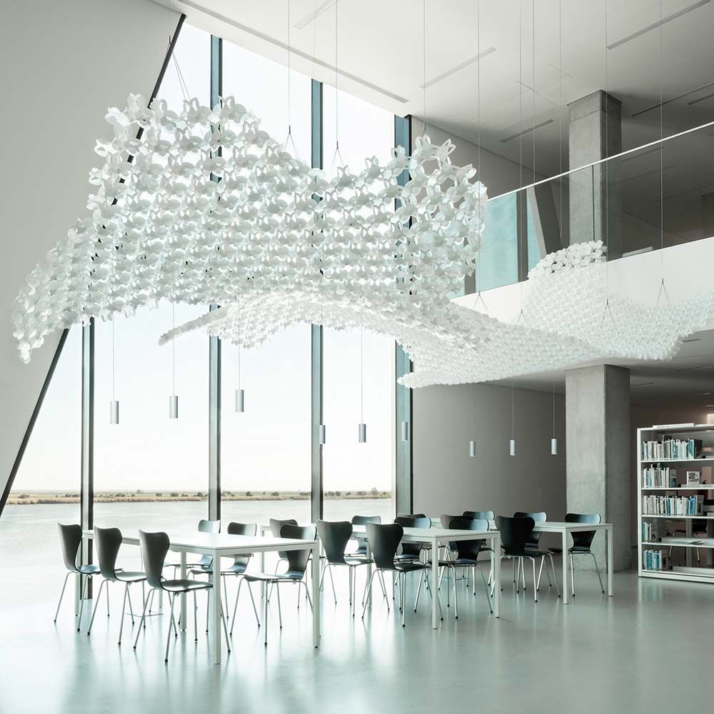 Hängende Slamp Nuvem Leuchte im modernen Raum mit Tischen und Stühlen, lichtdurchflutet durch große Fenster.