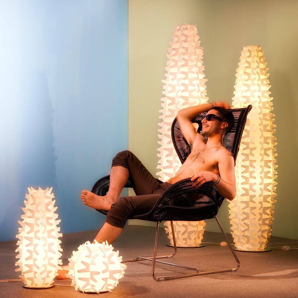 Slamp Stehleuchte Cactus XL Gold neben Mann in Relaxposition auf modernem Stuhl, stilvolles Ambiente