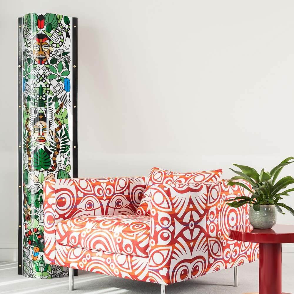 Slamp Stehleuchte Lafrique Extra Large Tube Schwarz neben buntem Sessel und Tisch, modernes Wohnzimmerdesign.