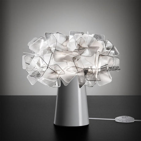 Luminária de mesa Slamp Clizia Branca sobre uma mesa, com um design único e moderno feito de formas transparentes.