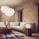 Slamp Tischlampe Veli Foliage in modernem Wohnzimmer, ergänzt mit stilvollen Möbeln und natürlicher Steinwand.
