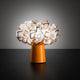 Slamp Tischleuchte Clizia Orange mit blütenförmigem Lampenschirm und orangefarbenem Sockel auf schwarzem Tisch.