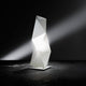 Slamp Tischleuchte Diamond Small Weiß mit geometrischem Design und indirekter Beleuchtung auf schwarzem Hintergrund.