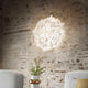 Slamp Wand- & Deckenlampe Veli Foliage an einer rustikalen Wand mit sanfter Beleuchtung.