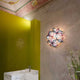 Slamp Wand- & Deckenleuchte La Vie Effektlampe in floralem Design an einer grünen Wand.