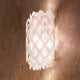 Slamp Wandlampe Charlotte Applique Weiß an einer Wand, mit wabenförmiger Struktur und sanftem Lichtspiel.