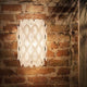 Slamp Wandlampe Charlotte Applique Weiß an einer Ziegelwand, mit wabenförmiger Struktur für weiches Lichtspiel.