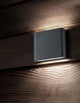 Soho LED Außenwandleuchte Qudadratisch Up & Down 3000K IP54 an Holzfassade montiert, warmweißes Licht abstrahlend.