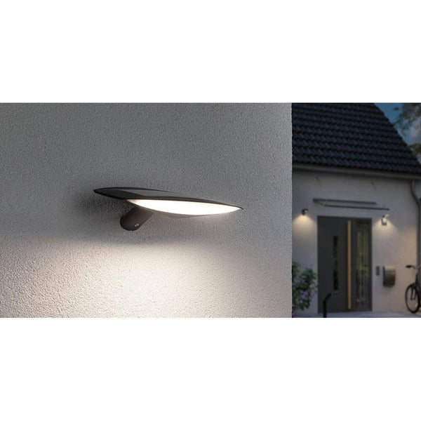 Solar LED Außenwandleuchte Kiran Bewegungssensor Anthrazit an einer Wand montiert mit warmem Licht.