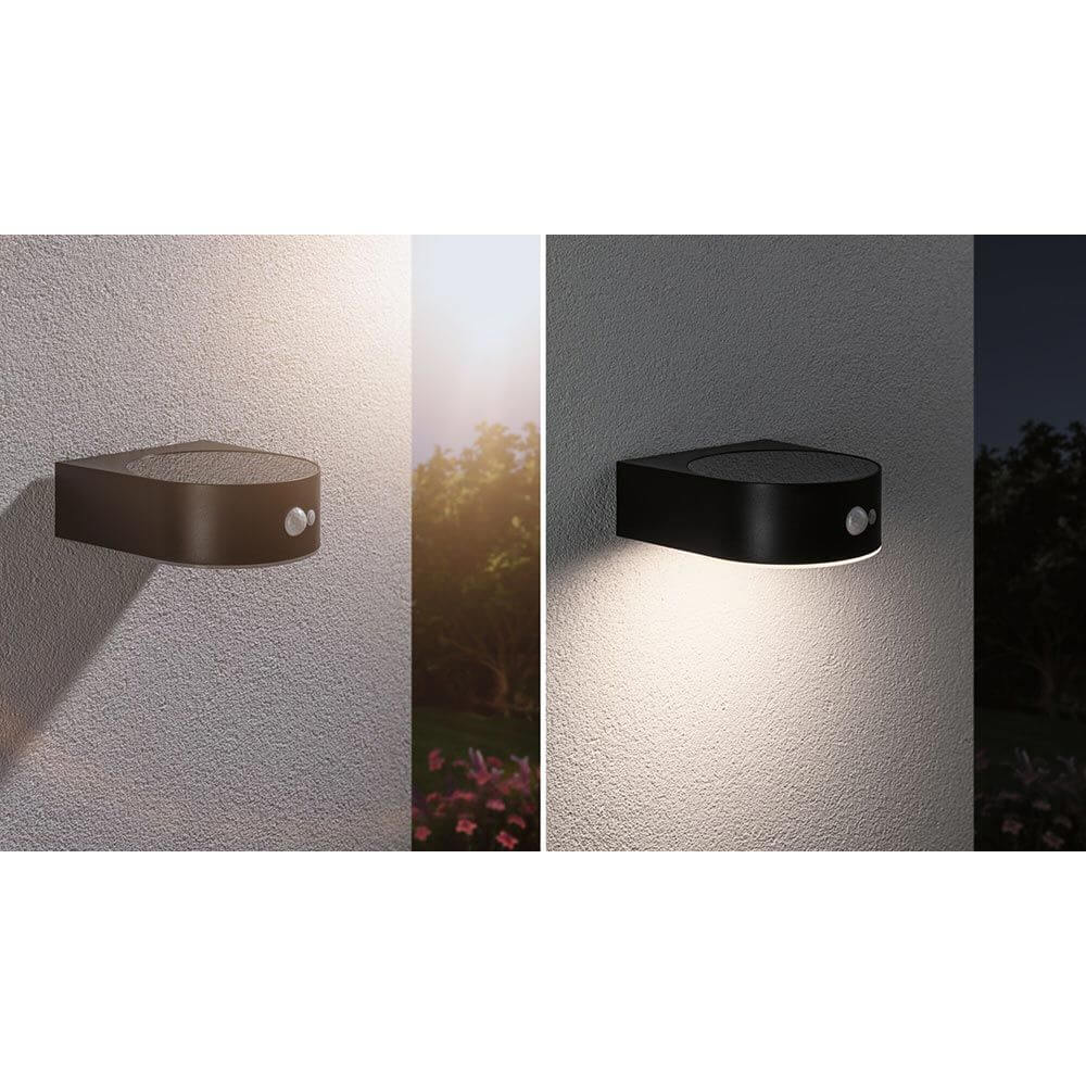 Solar LED Außenwandleuchte Eileen Sensor Schwarz an einer Wand montiert, bietet warmweißes Licht und Bewegungssensor.