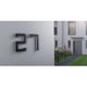 Moderne Hausnummer 27 aus Edelstahl an einer Wand, ideal für die äußere Beleuchtung und Kennzeichnung von Wohngebäuden.