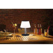 Lampe de table solaire LED Lillesol en acier inoxydable avec variateur à niveaux sur une table en extérieur, lumière chaleureuse avec des boissons.