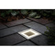 LED Solar Bodeneinbauleuchte Cube IP67 Edelstahl auf Gartenboden, beleuchtet durch Sonnenenergie.