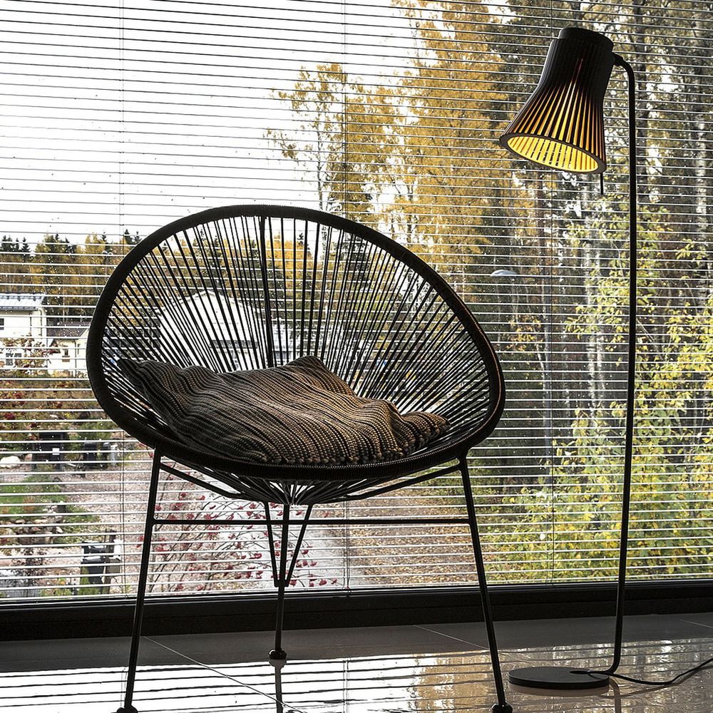 Elegante Standleuchte Petite 4610 aus Holz mit skandinavischem Design neben einem gemütlichen Sessel.