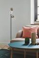 Stehlampe Arild mit zwei Lampenköpfen in modernem Design, elegant ergänzt durch bräunliche Messingdetails.