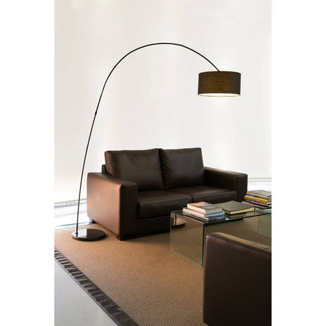 Bogen-Stehlampe Papua Schwarz neben einem modernen Sofa und einem Glastisch in einem eleganten Raum.