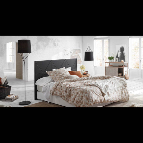 Stehlampe TREE Schwarz neben einem Bett in einem stilvollen Schlafzimmer mit floralen Bettüberwürfen.