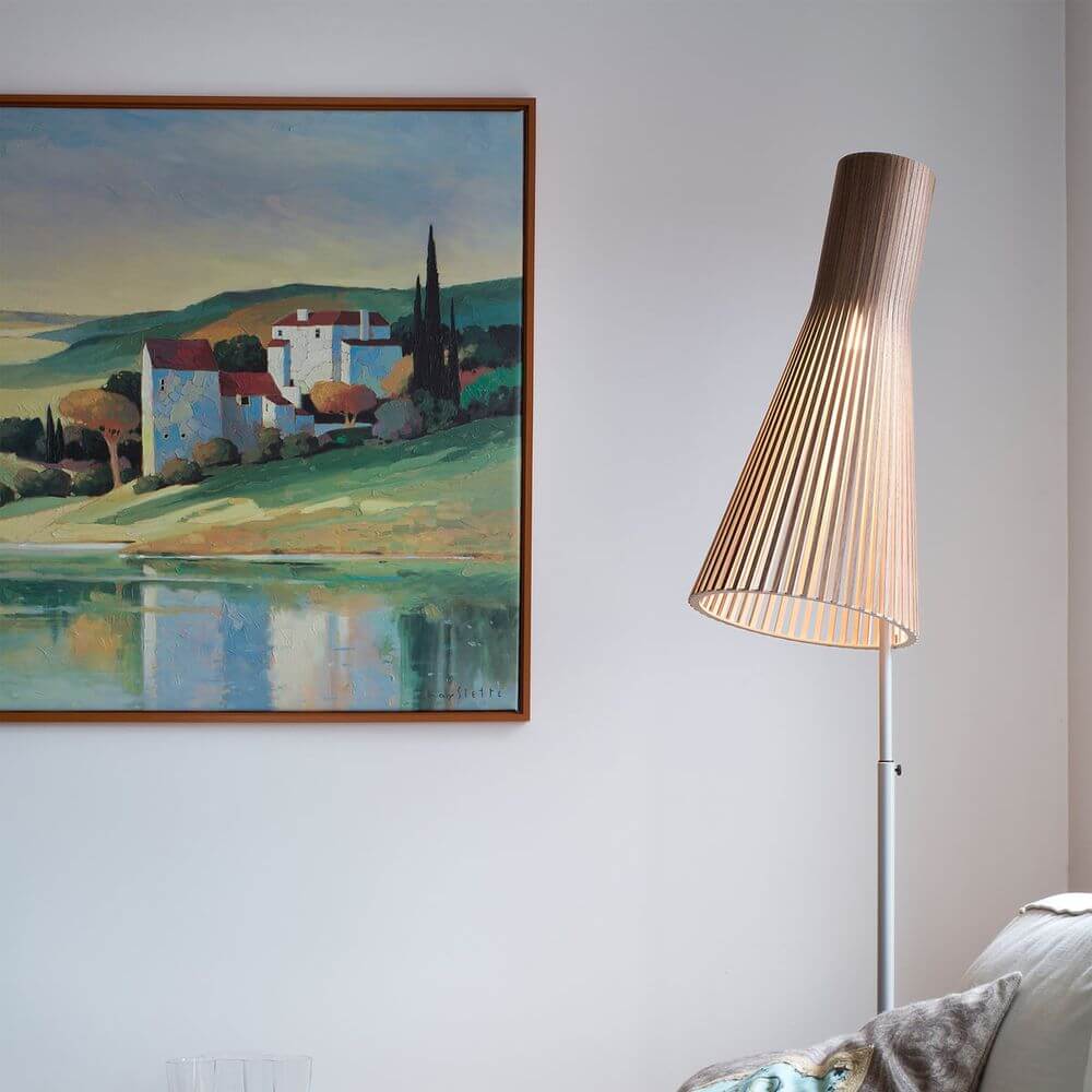 Stehleuchte Secto 4210 aus Holz 185cm neben einem farbenfrohen Landschaftsgemälde an einer Wand.