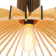 Detailansicht der Holz-Hängeleuchte Smukt mit leuchtender Glühlampe und Holzlamellen.